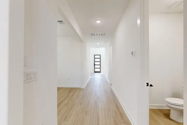 a view of a hallway with wooden floor and a bathroom