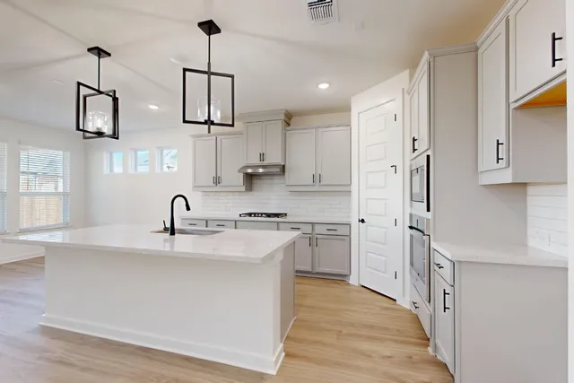 a kitchen with stainless steel appliances granite countertop a sink a refrigerator and a stove