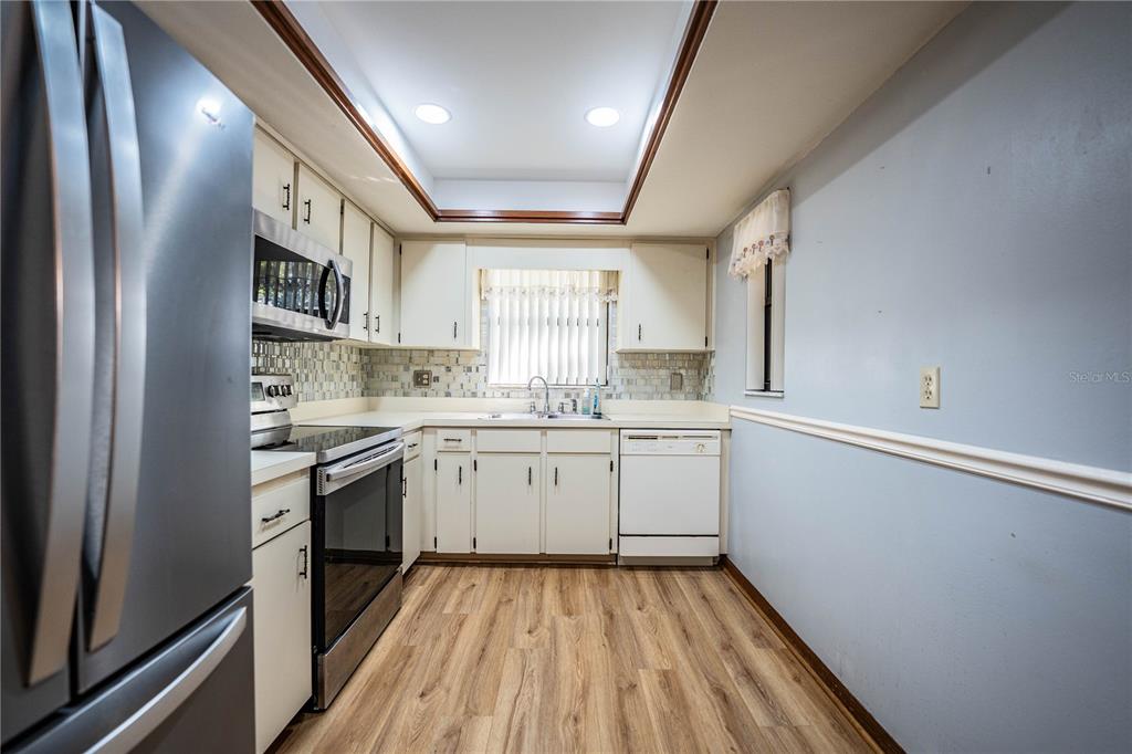 2025 Sylvester Road, Unit AA1 Lakeland, FL 33803 - Photo 8 of 65 a kitchen with granite countertop white cabinets stainless steel appliances a sink and a window