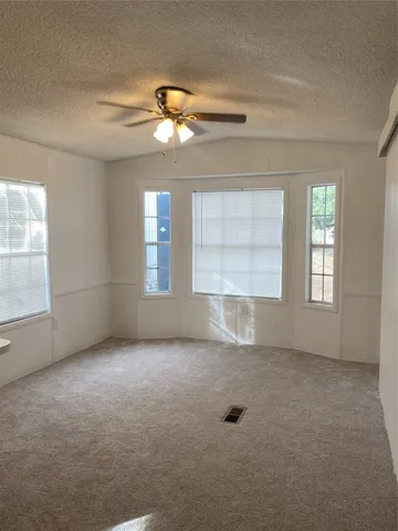 an empty room with windows and chandelier fan