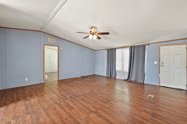 a view of an empty room with window and a ceiling fan