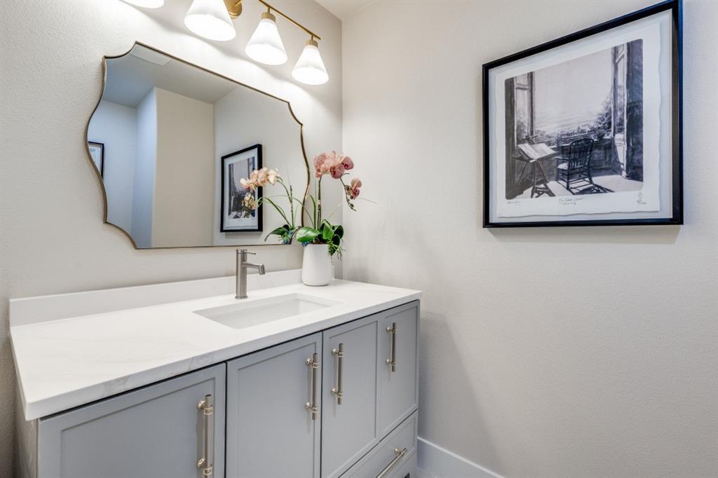 7115 Meadow Road Dallas, TX 75230 - Photo 12 of 22 Modern vanity featuring a white countertop, an integrated rectangular sink, and light gray cabinetry with brushed nickel hardware