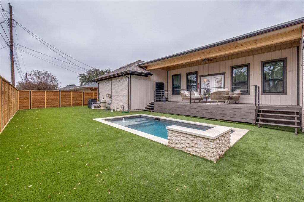 7115 Meadow Road Dallas, TX 75230 - Photo 18 of 22 The property features an extensive backyard with a rectangular pool, a stone-clad raised planter, and a spacious deck