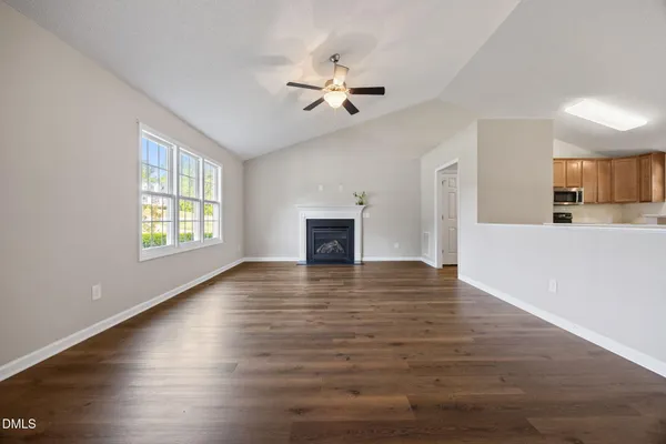 a view of an empty room with window and wooden floor