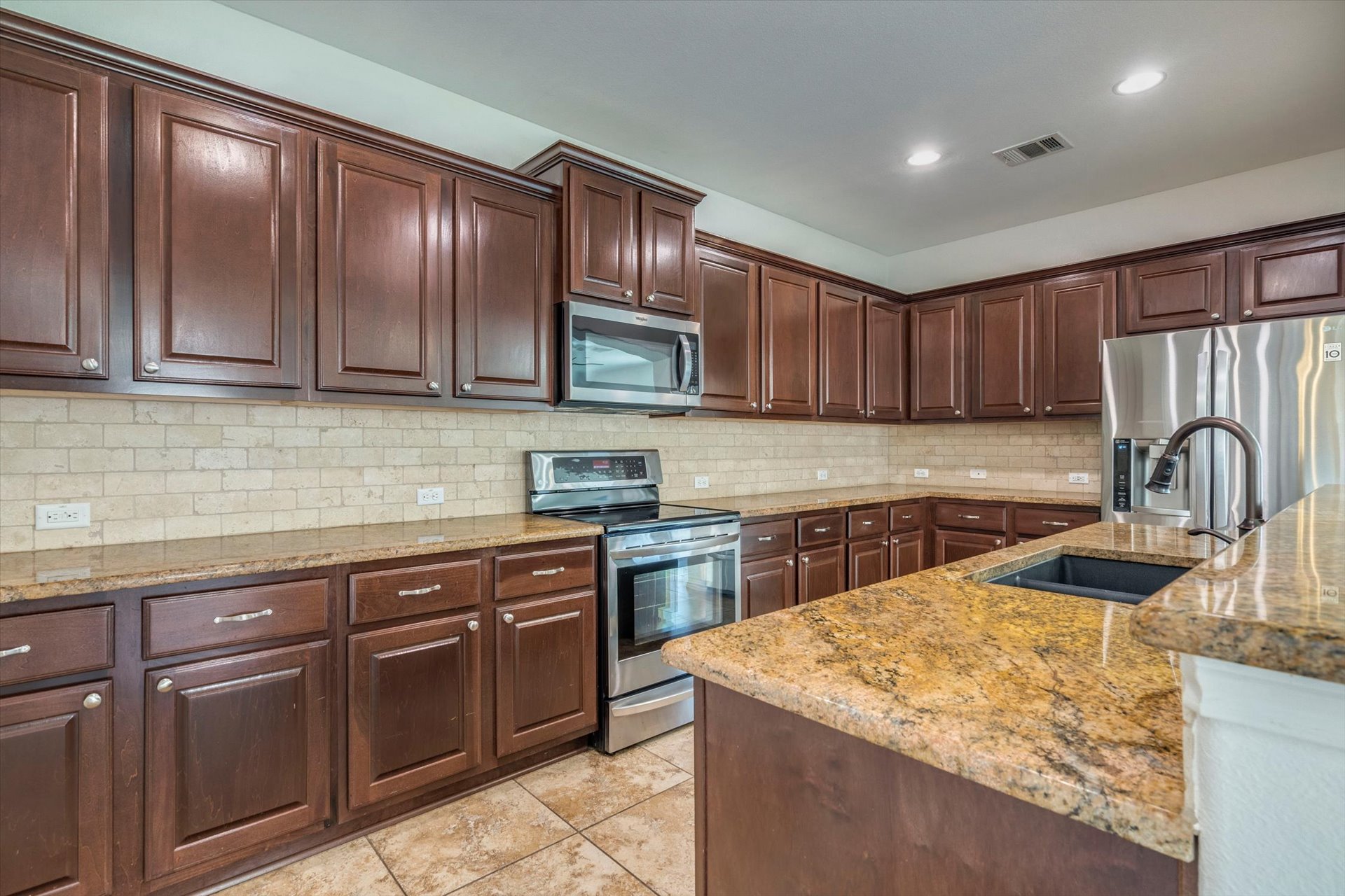 16829 Ruggio Road Pflugerville, TX 78660 - Photo 11 of 40 a kitchen with stainless steel appliances granite countertop wooden cabinets a stove top oven a sink and dishwasher