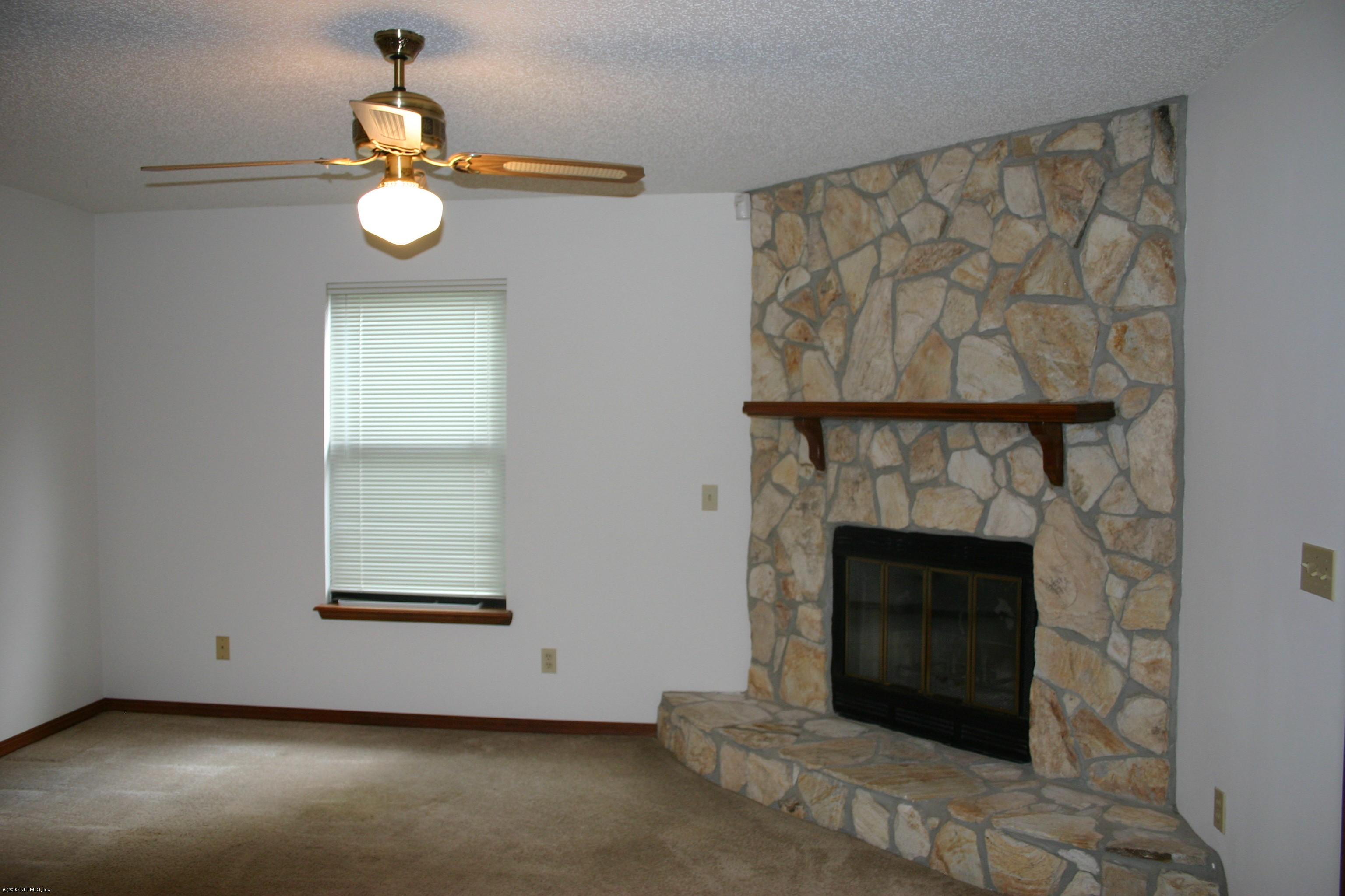 9231 Hipps Road Jacksonville, FL 32222 - Photo 4 of 6 an empty room with windows and fireplace