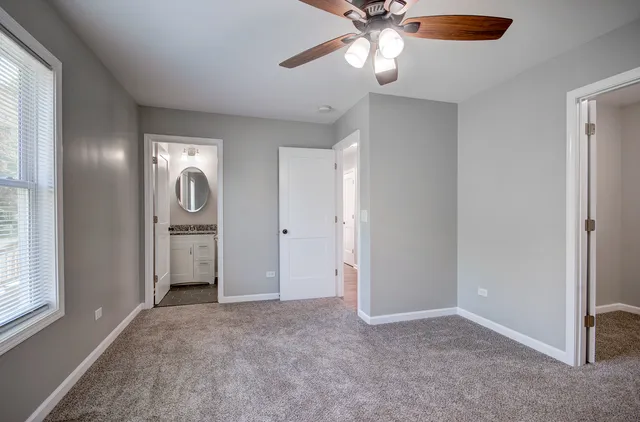 an empty room with windows and fan