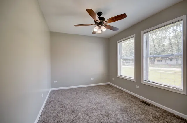 an empty room with windows and fan