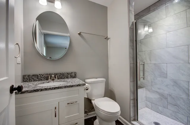 a bathroom with a granite countertop toilet sink and mirror