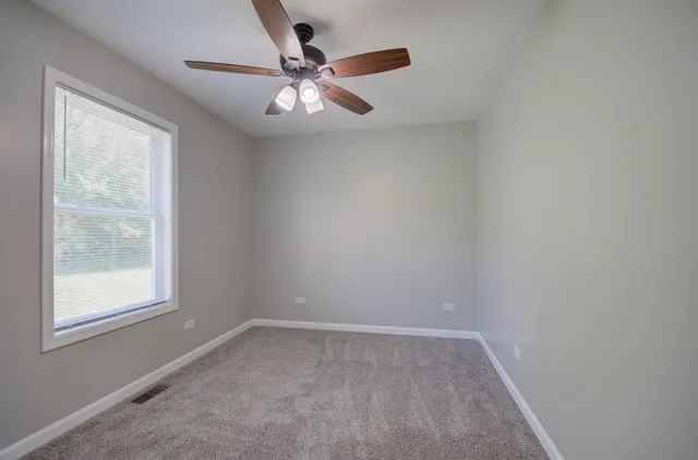 an empty room with a window and a fan