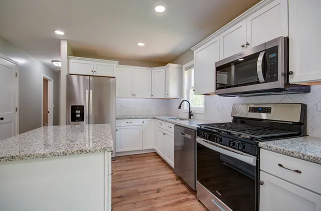 a kitchen with stainless steel appliances granite countertop a stove a refrigerator and a microwave