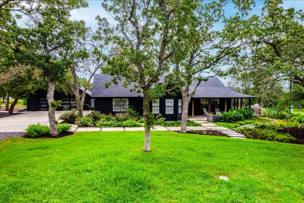 a front view of a house with garden and trees