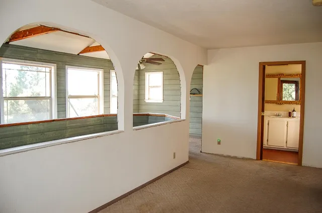 a view of small white house with a small yard and plants