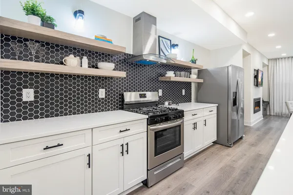 a kitchen with stainless steel appliances a refrigerator and a wooden floor