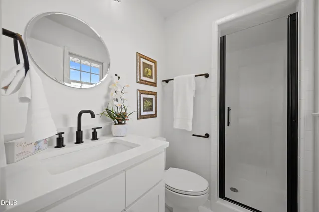 a bathroom with a toilet a sink a mirror a window and vanity