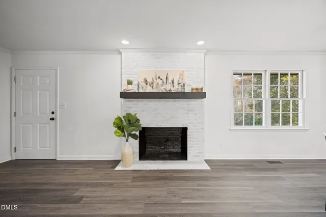 a view of an empty room with wooden floor and a fireplace