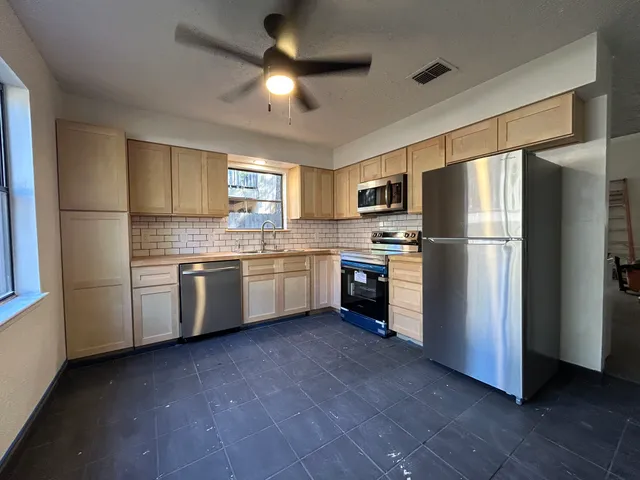 a kitchen with stainless steel appliances a refrigerator a sink a stove a microwave and island