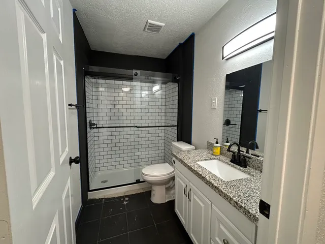 a bathroom with a granite countertop sink toilet mirror and shower