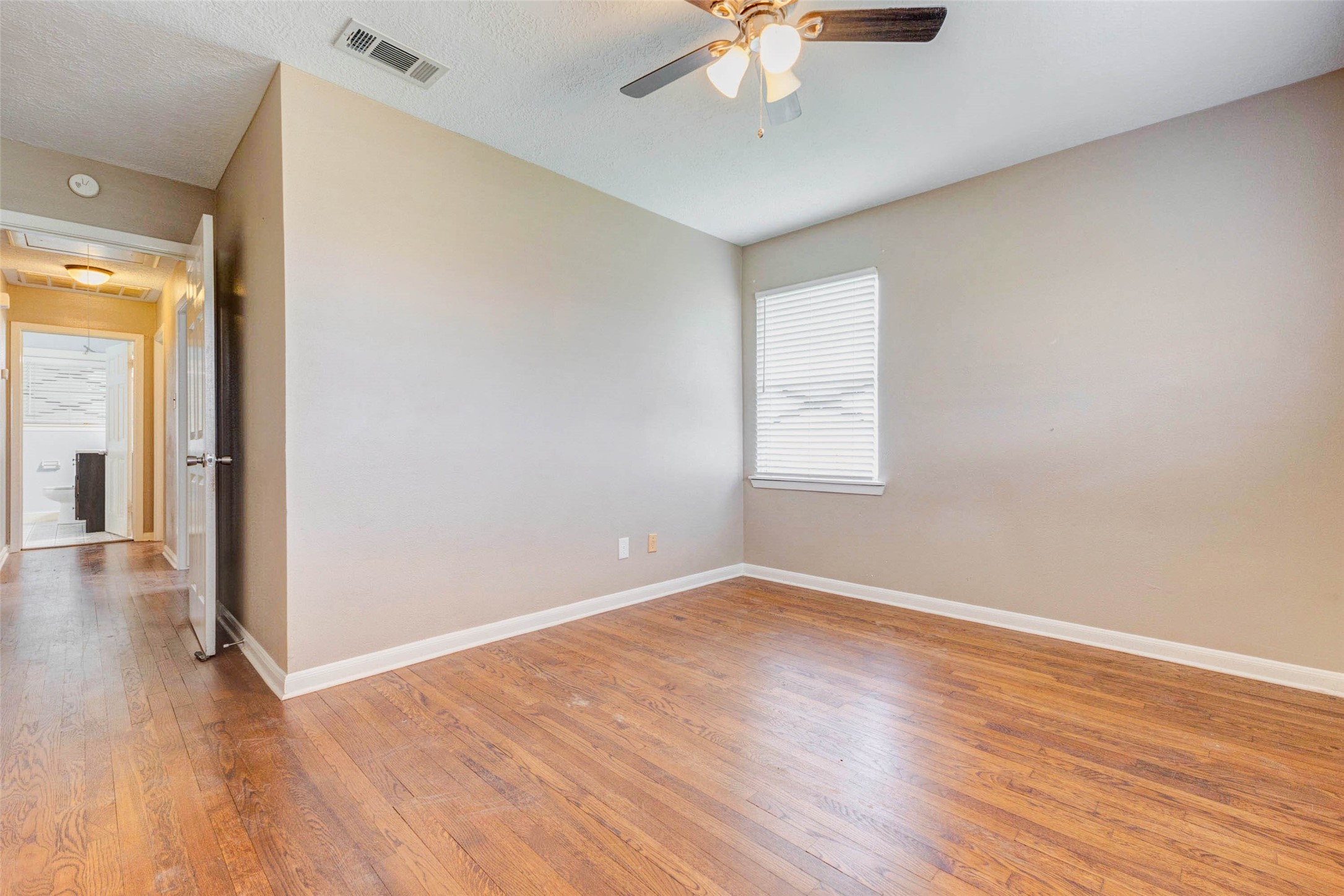 411 Burke Road Pasadena, TX 77506 - Photo 7 of 24 an empty room with wooden floor chandelier fan and windows