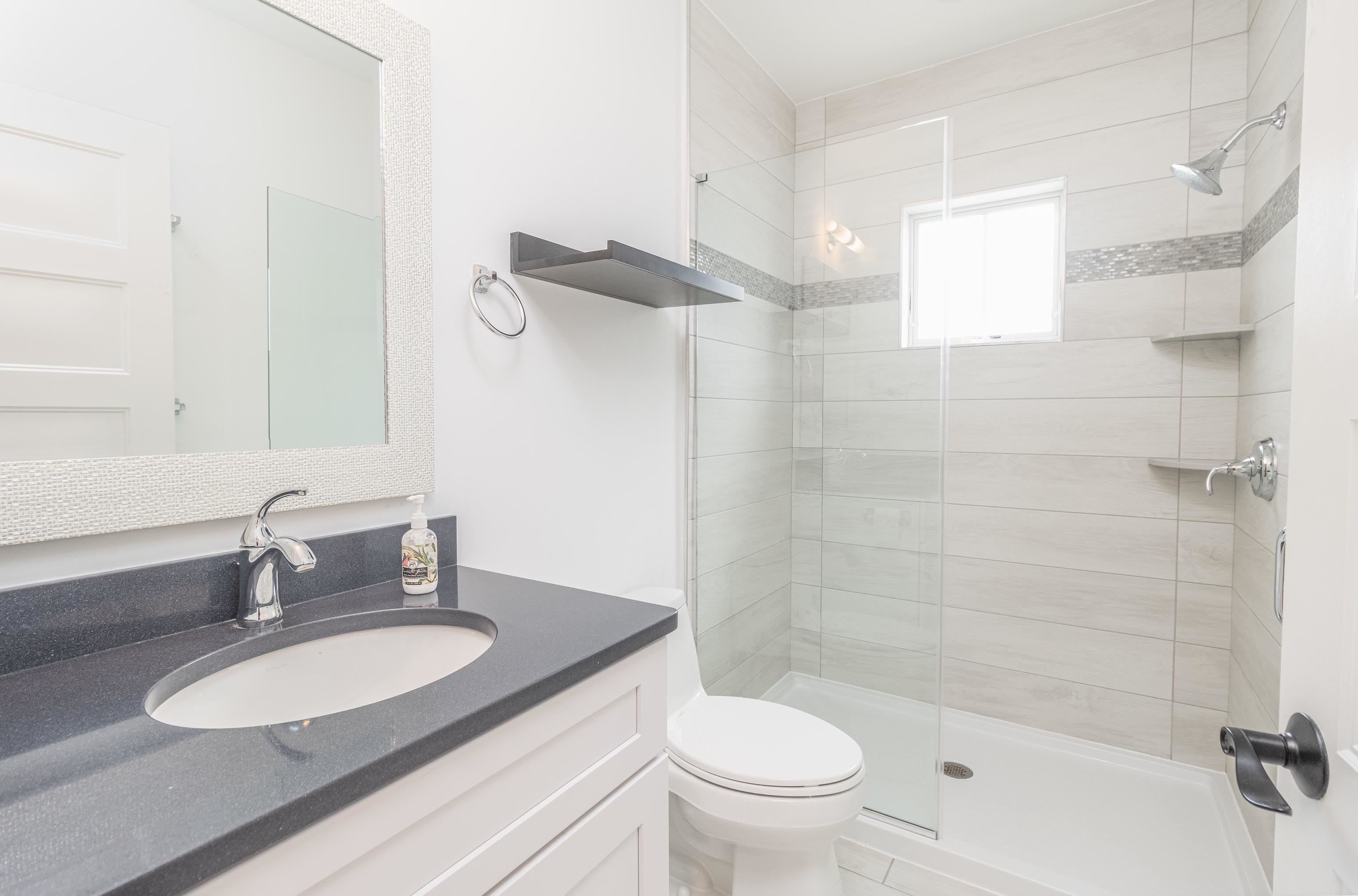 25 West 32nd Avalon, NJ 08202 - Photo 18 of 40 a bathroom with a granite countertop sink toilet a mirror and shower