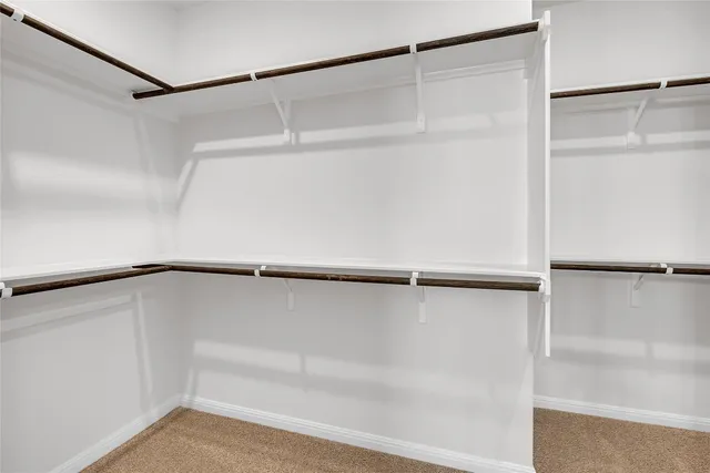 a view of an empty room with a kitchen and a window