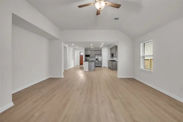 a kitchen with stainless steel appliances granite countertop a stove a sink a refrigerator and white cabinets with wooden floor