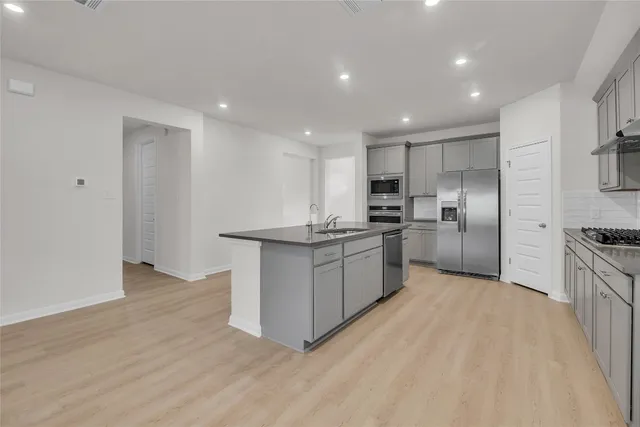 a kitchen with kitchen island granite countertop a sink stainless steel appliances and cabinets
