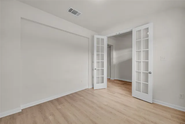 a view of an empty room with wooden floor and closet