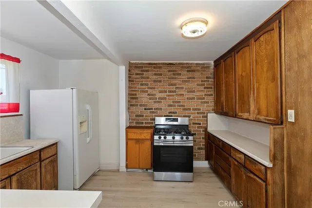 a kitchen with stainless steel appliances granite countertop a stove a refrigerator and a sink with wooden cabinets