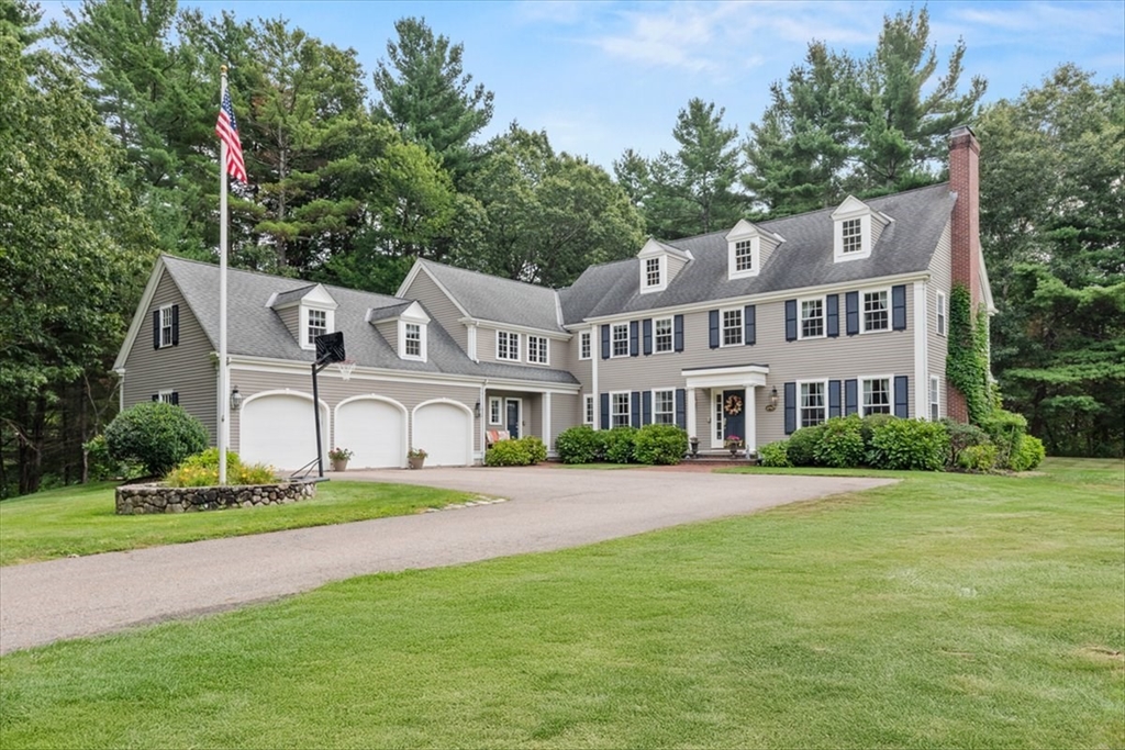 a front view of a house with a garden and trees