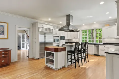 a kitchen with stainless steel appliances a dining table chairs stove and cabinets