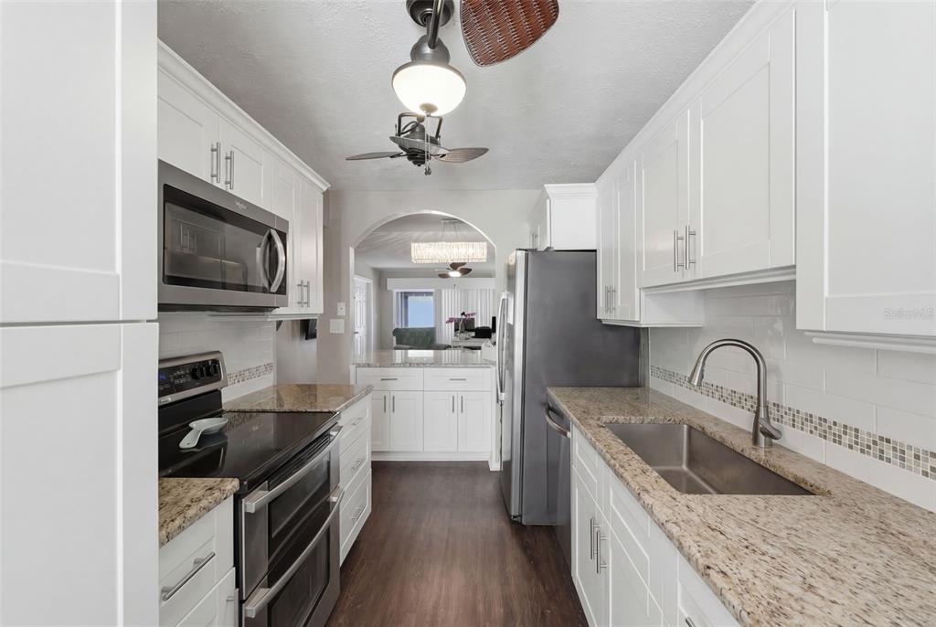 2074 Sunset Point Road, Unit 137 Clearwater, FL 33765 - Photo 11 of 32 a kitchen with stainless steel appliances granite countertop a sink a stove top oven a refrigerator cabinets and chairs