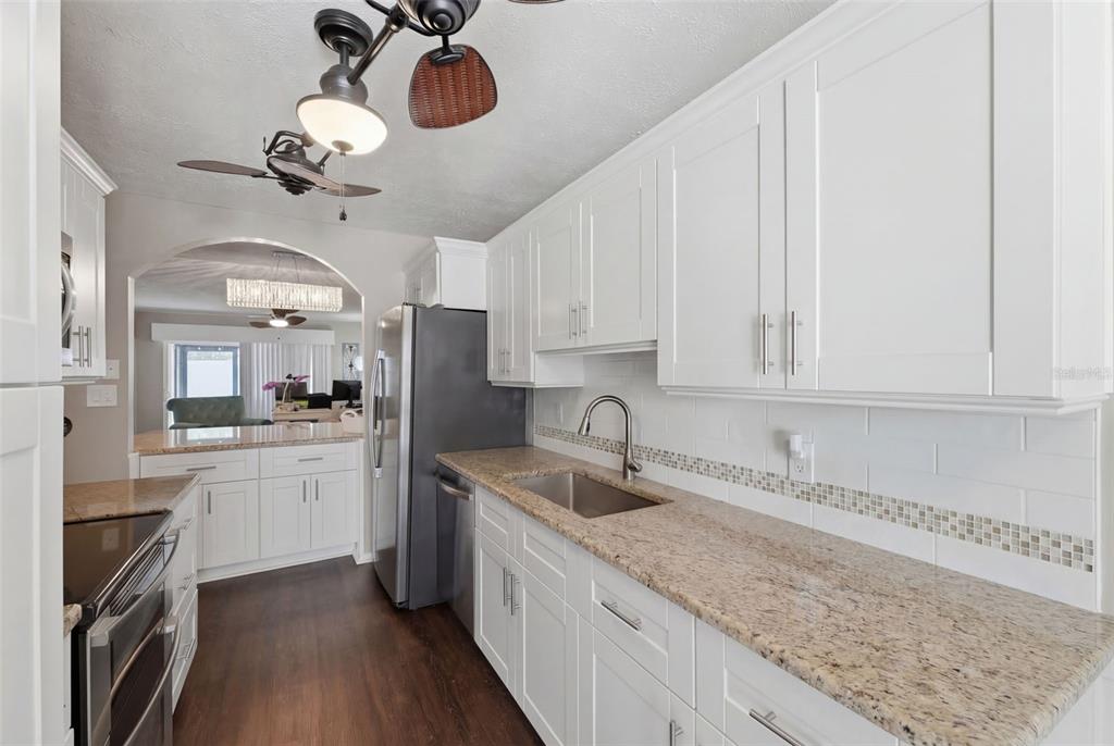 2074 Sunset Point Road, Unit 137 Clearwater, FL 33765 - Photo 12 of 32 a kitchen with a sink dishwasher and white cabinets with wooden floor