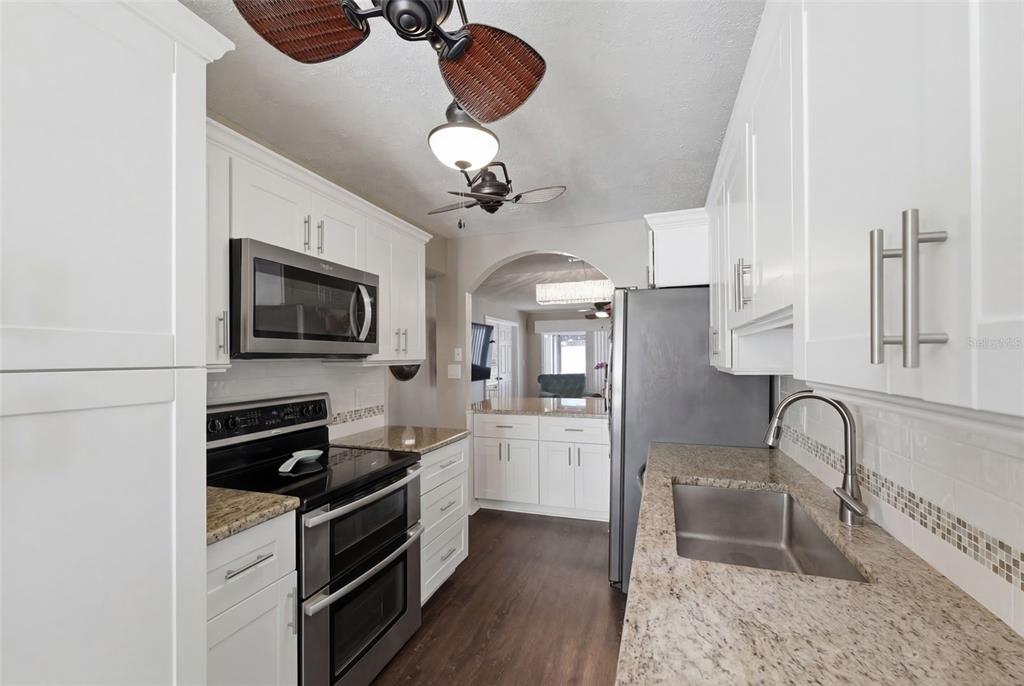 2074 Sunset Point Road, Unit 137 Clearwater, FL 33765 - Photo 13 of 32 a kitchen with stainless steel appliances granite countertop a stove top oven a sink dishwasher a dining table and chairs with wooden floor