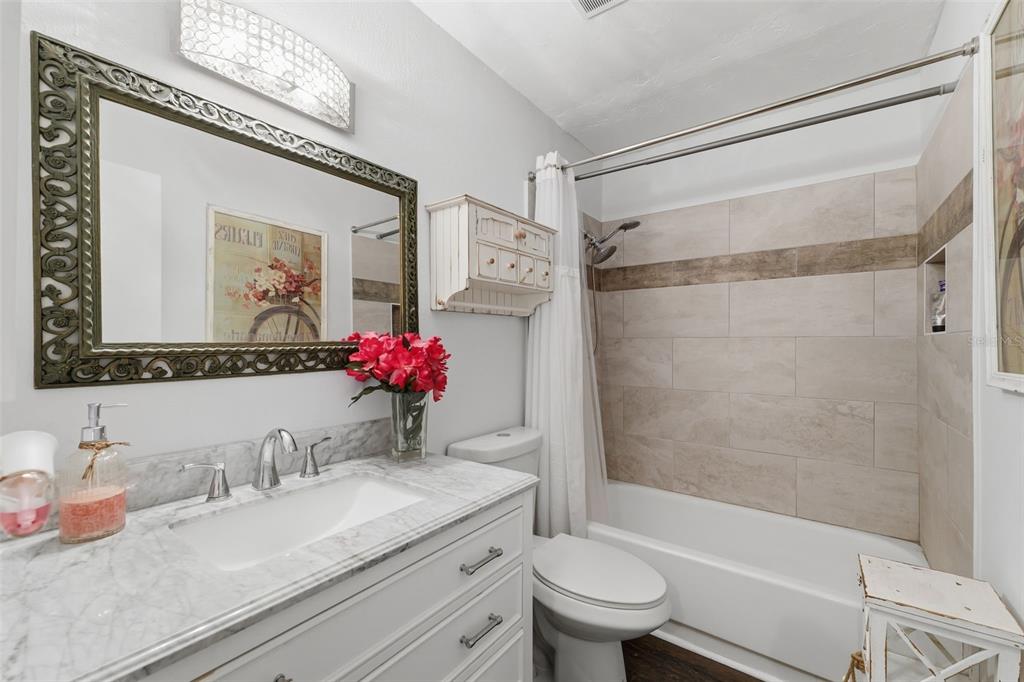2074 Sunset Point Road, Unit 137 Clearwater, FL 33765 - Photo 20 of 32 a bathroom with a granite countertop sink mirror toilet and bathtub