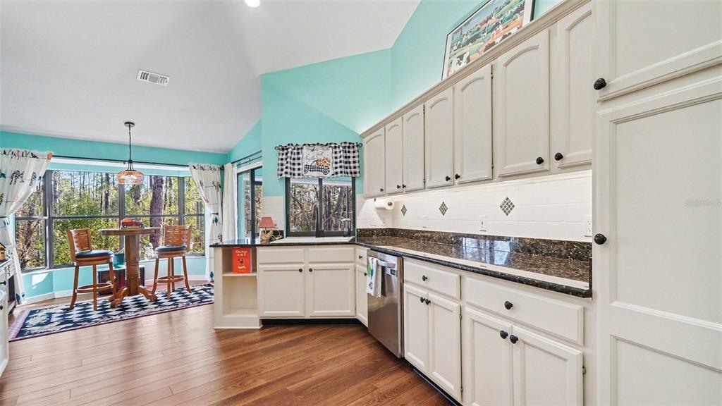 17 Longleaf Court Homosassa, FL 34446 - Photo 11 of 30 a kitchen with granite countertop a stove a sink and white cabinets with wooden floor