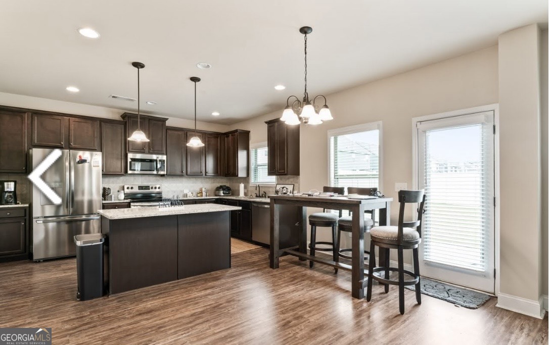 6014 Prodigy Lane Locust Grove, GA 30248 - Photo 3 of 7 a kitchen with stainless steel appliances granite countertop a refrigerator a stove a sink dishwasher a dining table and chairs with wooden floor
