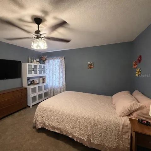 a spacious bedroom with a bed and a flat screen tv