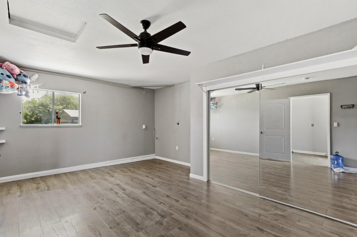 7208 7th Street Rio Linda, CA 95673 - Photo 13 of 41 an empty room to hallway with wooden floor a ceiling fan and a window