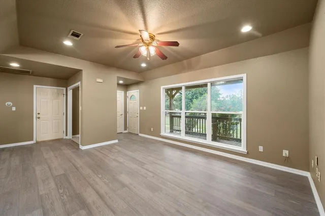 a view of an empty room with a window and wooden floor