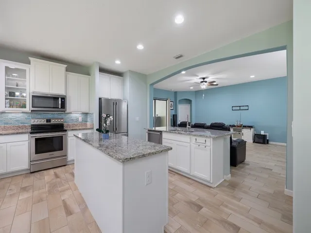 a kitchen with kitchen island granite countertop a sink and cabinets