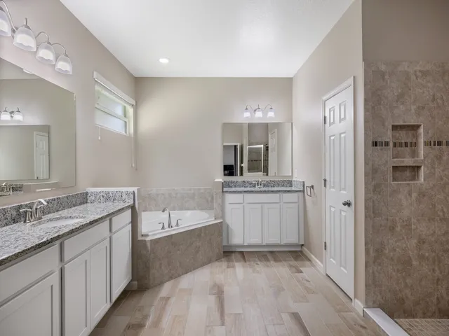 a bathroom with a granite countertop tub sink and mirror