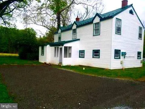 a view of a white house with a big yard and large trees