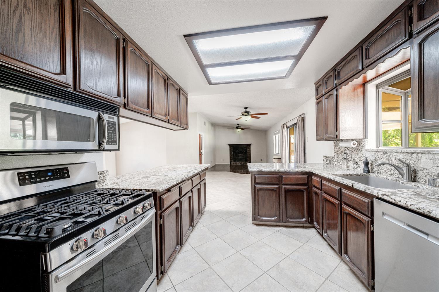 12502 Road 37 1/2 Madera, CA 93636 - Photo 19 of 79 a kitchen with stainless steel appliances granite countertop a stove top oven a sink dishwasher a refrigerator and cabinets with wooden floor