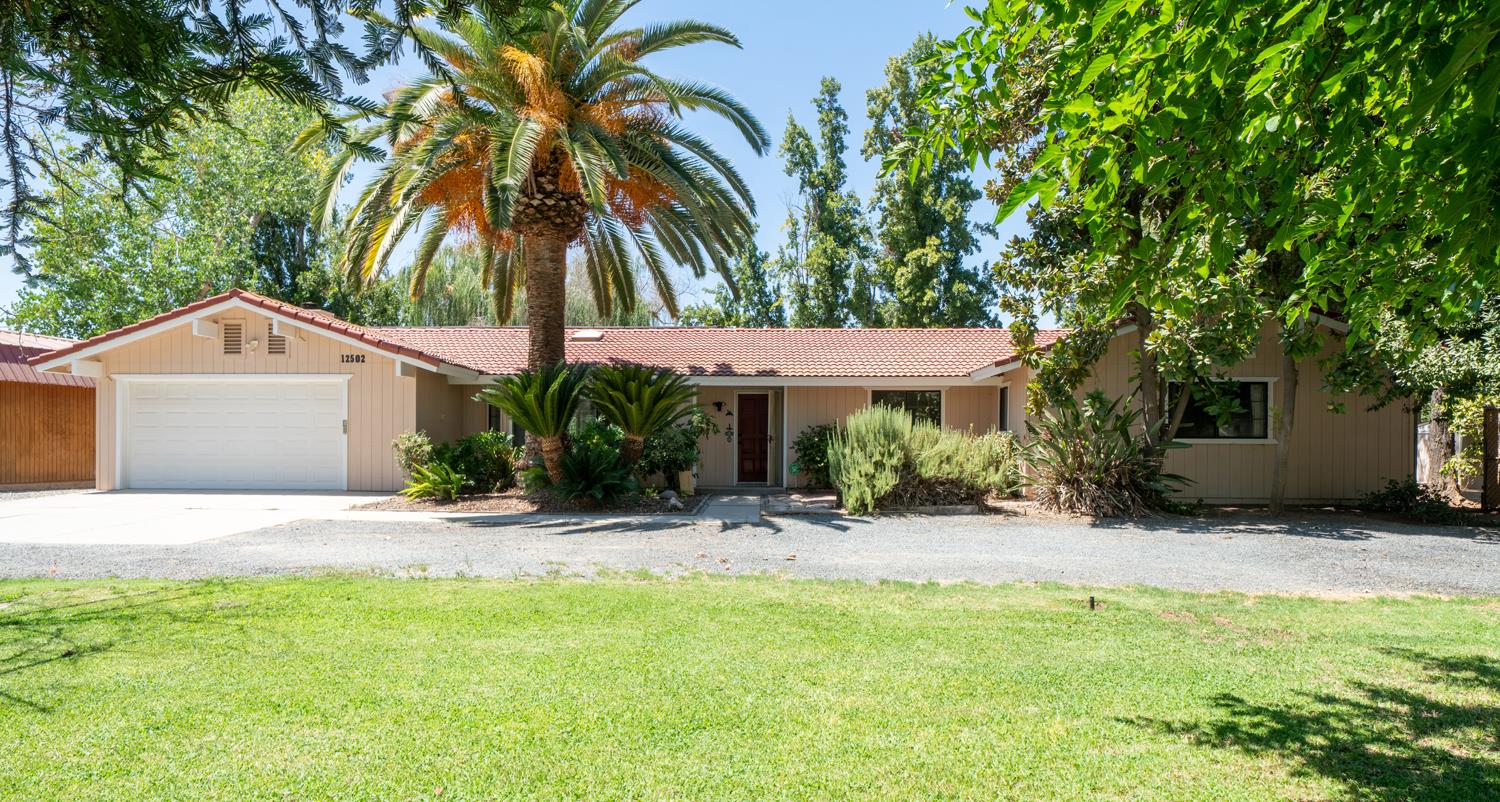 12502 Road 37 1/2 Madera, CA 93636 - Photo 7 of 79 a backyard of a house with table and chairs under an umbrella