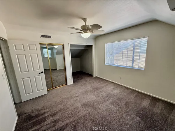 an empty room with windows and fan