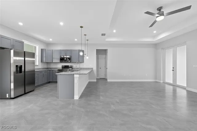 a large kitchen with granite countertop a sink a counter top space and stainless steel appliances