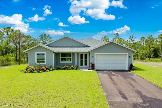 a front view of house with yard and trees in the background