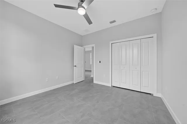 an empty room with windows and ceiling fan