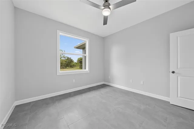 a view of an empty room and chandelier fan